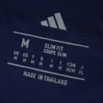 Size label inside Ajax Away 2025/26 Fan Version jersey, showing medium slim fit and made in Thailand.