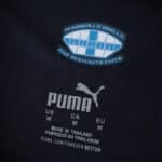 Close-up of Olympique Marseille Away 2025/26 Player Version jersey label with club crest and Puma logo.