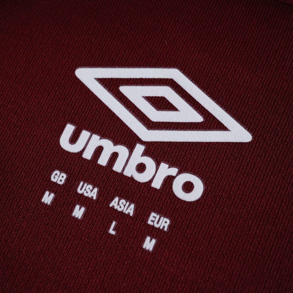 Close-up of Umbro logo and size chart on the West Ham United Home 2025/26 Fan Version jersey fabric.