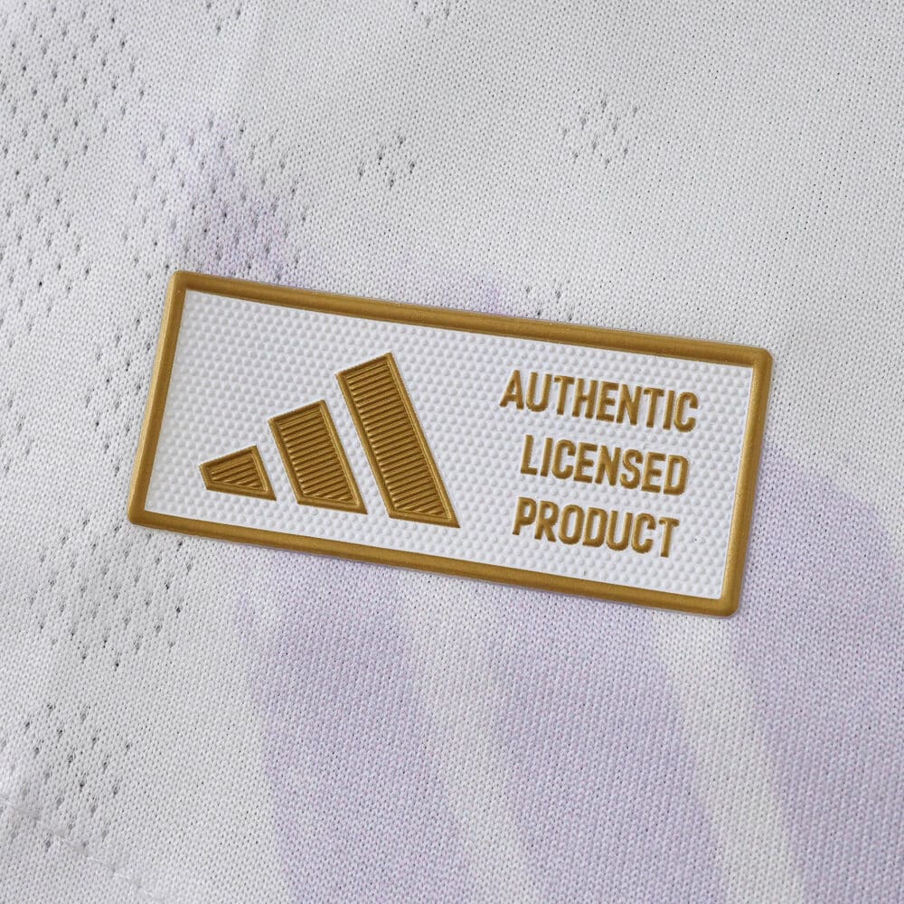 Close-up of gold "Authentic Licensed Product" badge on the Manchester United 2025/26 away player jersey.