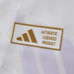 Close-up of gold "Authentic Licensed Product" badge on the Manchester United 2025/26 away player jersey.