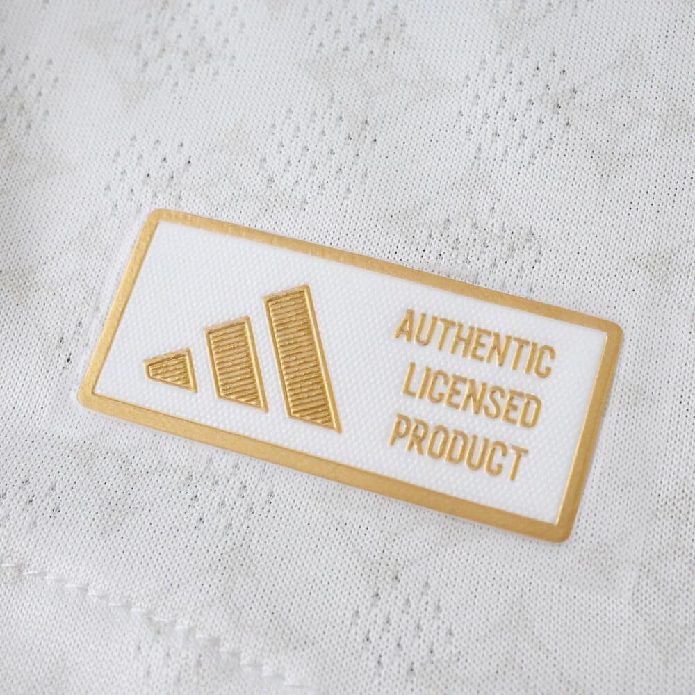Close-up of the "Authentic Licensed Product" badge on the Olympique Lyonnais 2025/26 home player jersey.
