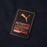 Close-up of the "Authentic Licensed Football" Puma badge on the Olympique Marseille 2025/26 away jersey.