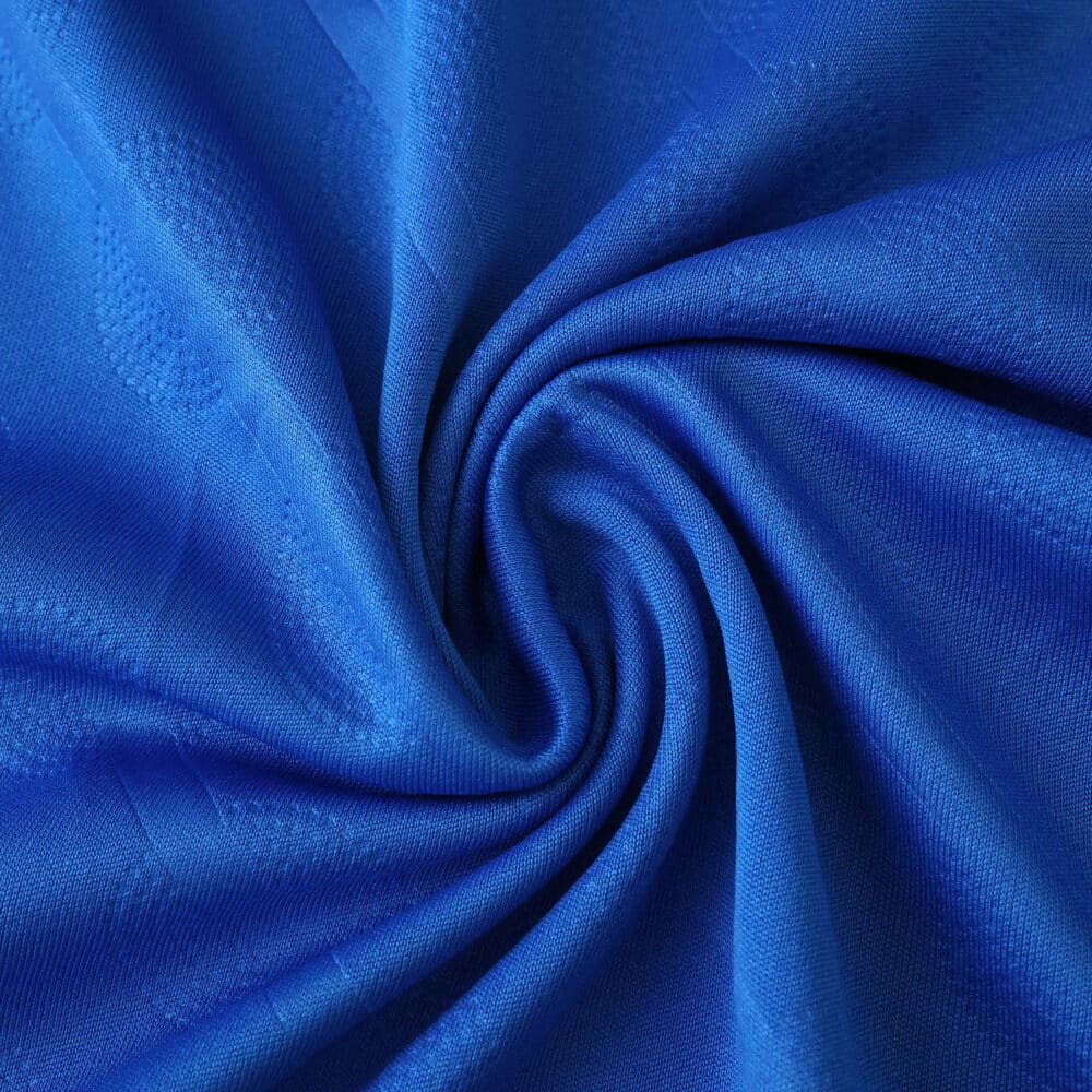 Close-up of blue Real Madrid Third 2025/26 Fan Version jersey fabric, showing texture and swirl pattern.