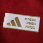 Close-up of the gold Adidas "Authentic Licensed Product" badge on the Roma 2025/26 home player jersey.