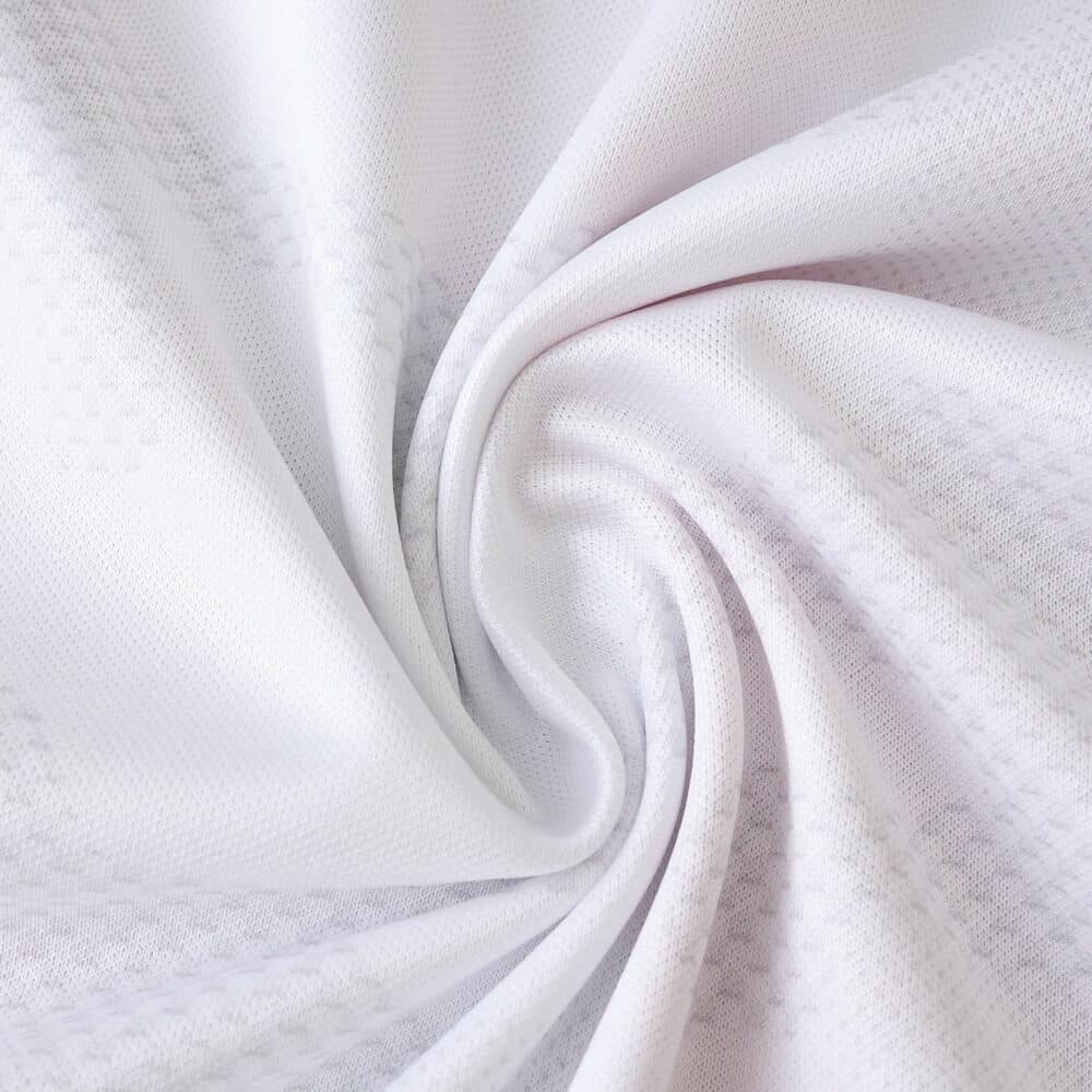 Close-up of the white FC Köln 2025/26 home fan jersey fabric showing texture and subtle pattern.