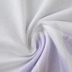Close-up of Manchester United 2025/26 away player jersey fabric showing white and light purple mesh texture.