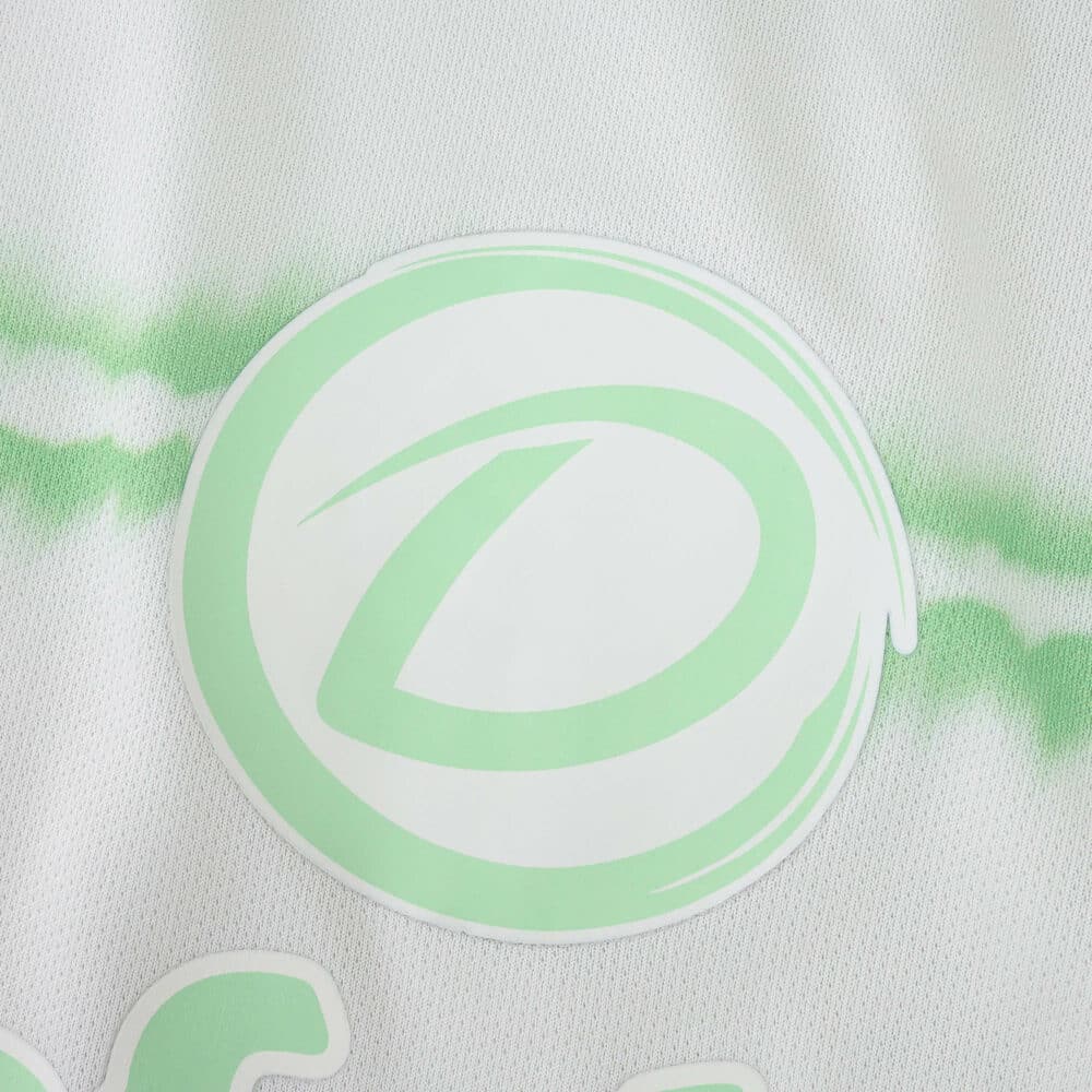 Close-up of the Celtic Third 2025/26 fan jersey featuring a green crest on white fabric with a subtle pattern.