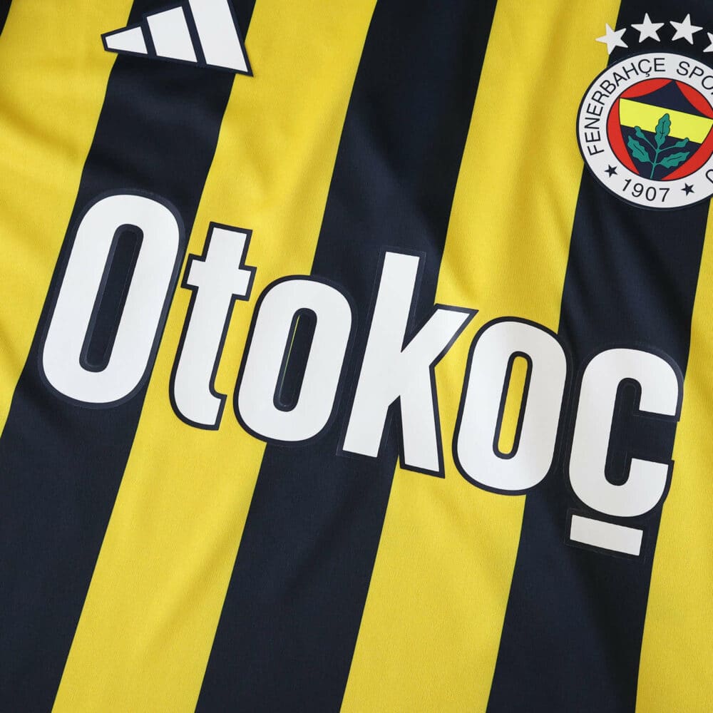 Close-up of Fenerbahce 2025/26 home fan jersey with sponsor logo and club crest on yellow and navy stripes.