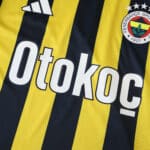 Close-up of Fenerbahce 2025/26 home fan jersey with sponsor logo and club crest on yellow and navy stripes.