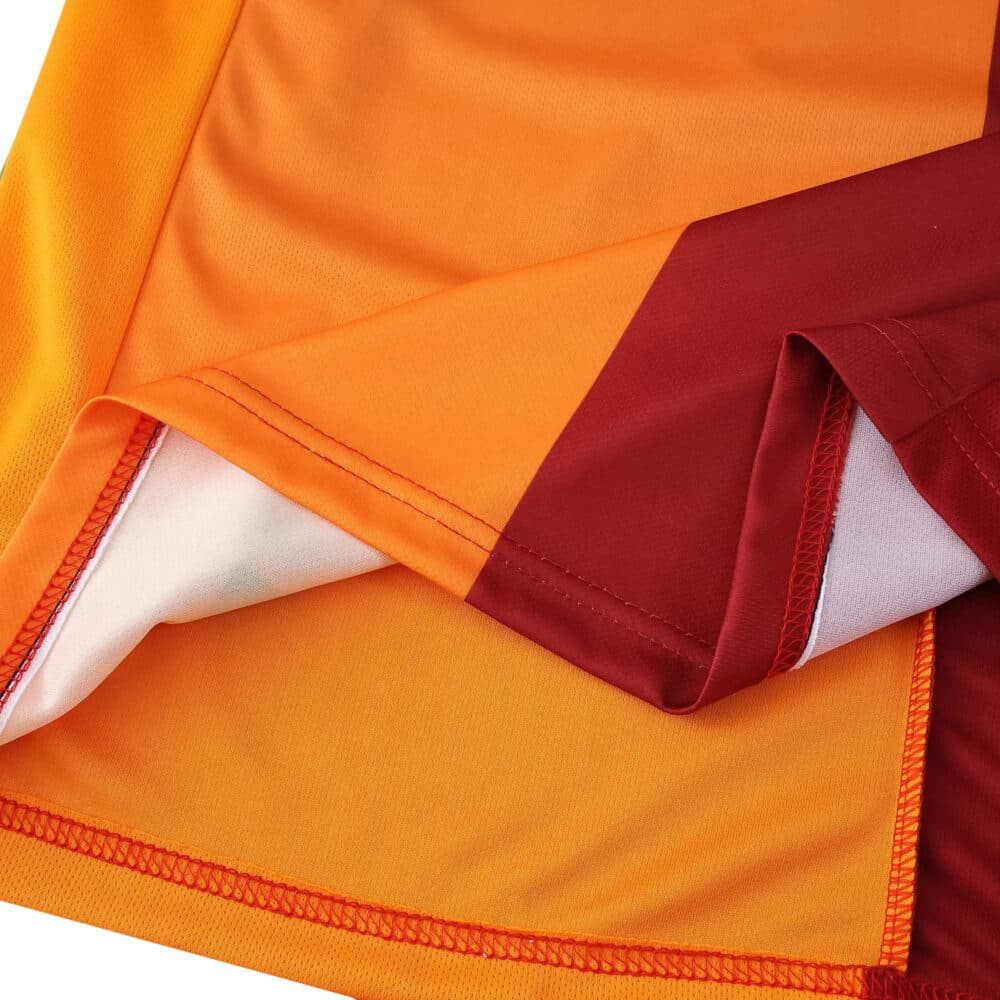 Close-up of the Galatasaray Home 2025/26 Fan Version jersey showing orange and red fabric detail.