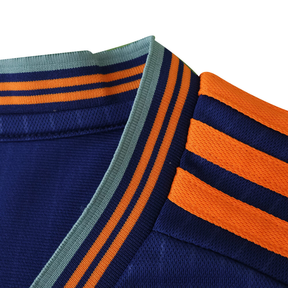 Close-up of the Newcastle United 2025/26 third fan jersey with orange and navy stripes on the collar and shoulder.