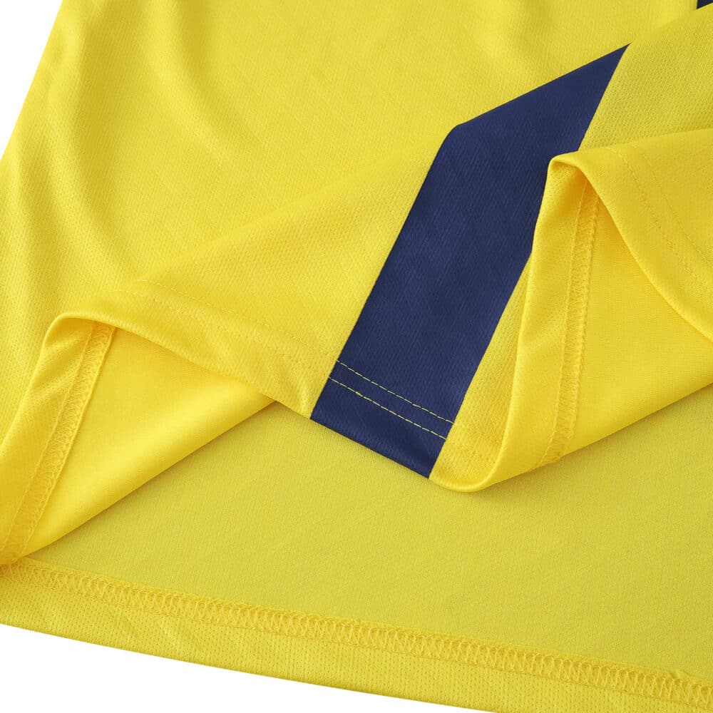 Close-up of Villarreal 2025/26 home fan jersey hem, featuring yellow fabric and a blue diagonal detail.