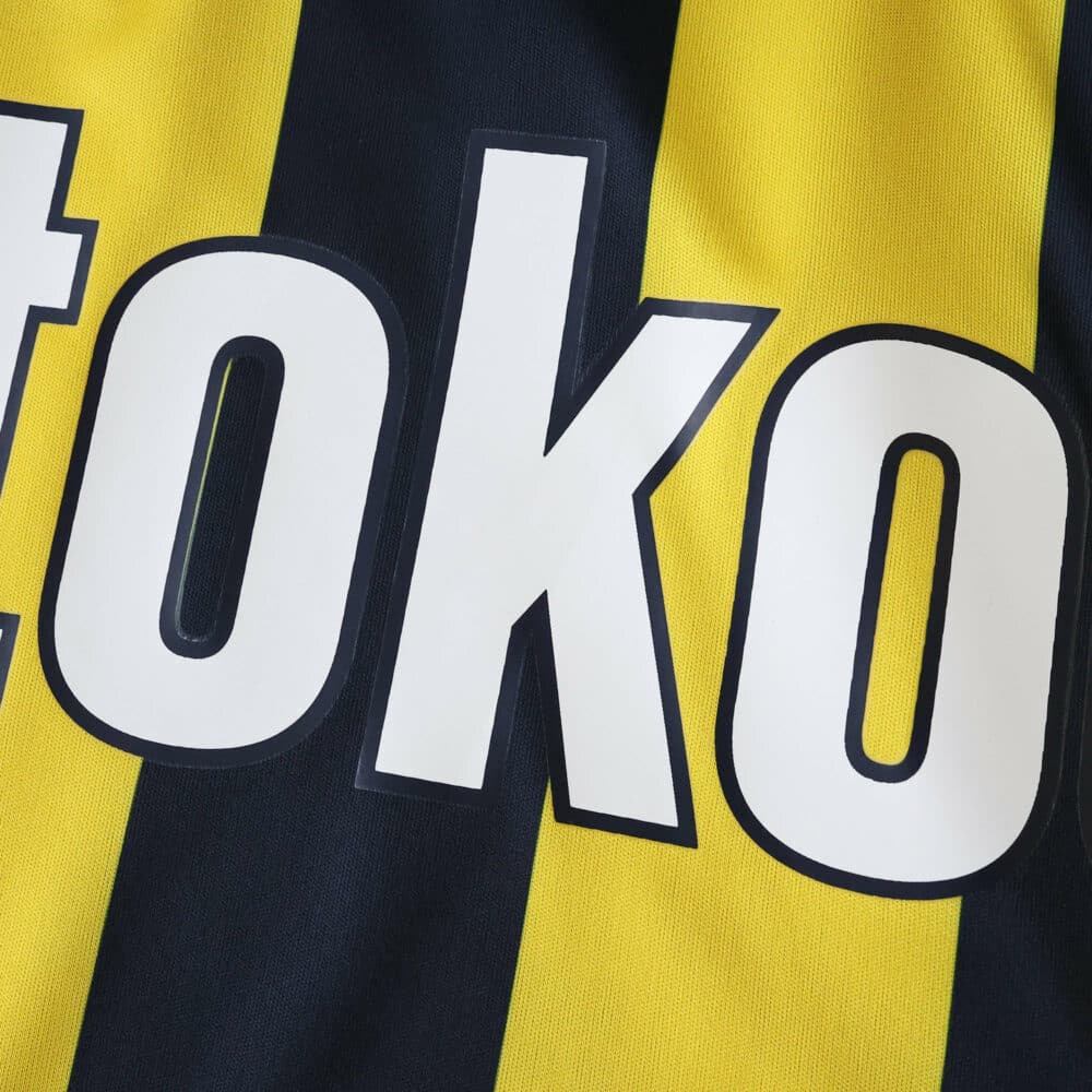 Close-up of Fenerbahce 2025/26 home fan jersey showing yellow and navy stripes with sponsor text.