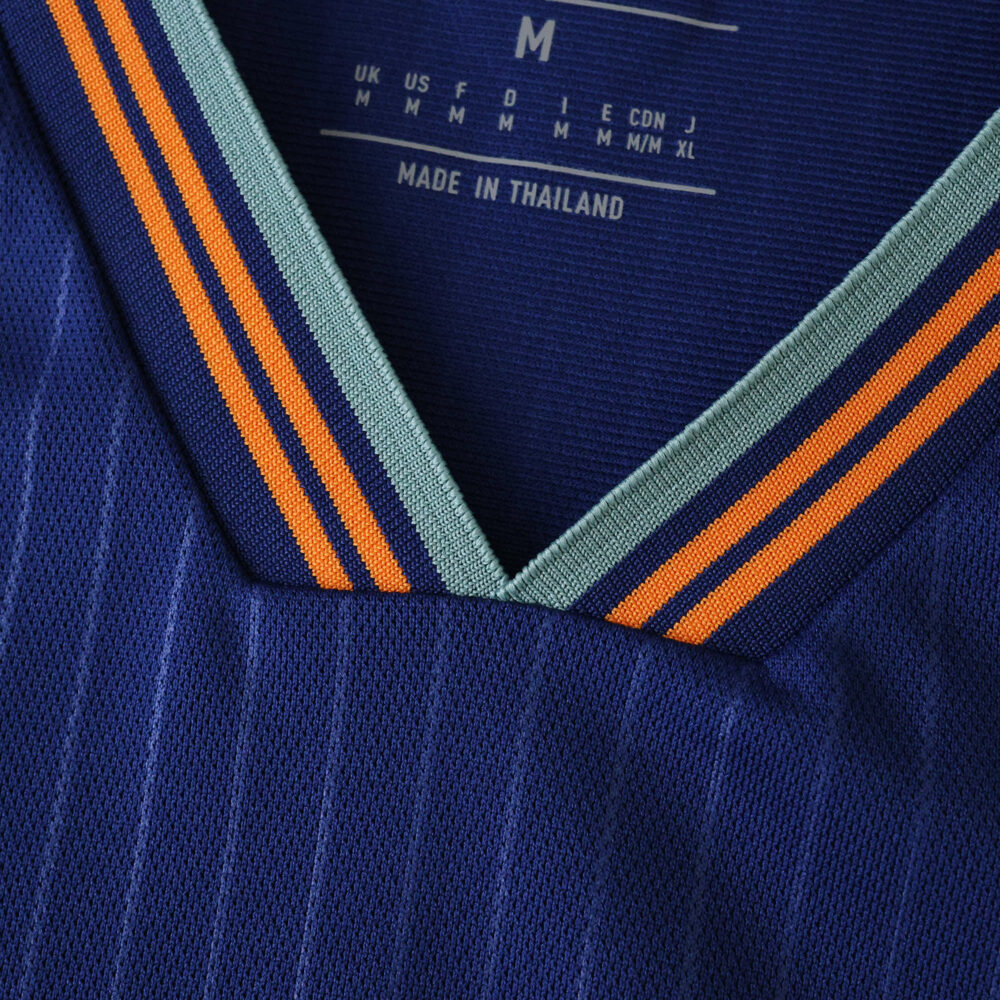 Close-up of the Newcastle United 2025/26 third fan jersey collar in blue with orange and teal stripes.