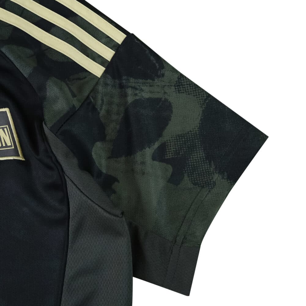 Detail of Union Berlin Away 2025/26 Fan Version jersey sleeve with dark camo pattern and gold stripes.