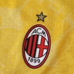 AC Milan 2025/26 Third Player Version jersey detail with club crest and star on yellow fabric.