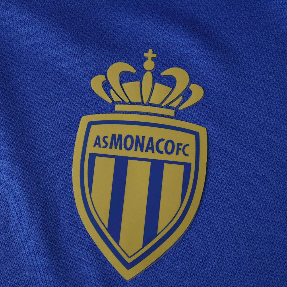 Close-up of the AS Monaco FC crest on the blue 2025/26 away fan version jersey fabric.