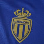 Close-up of the AS Monaco FC crest on the blue 2025/26 away fan version jersey fabric.