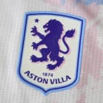 Close-up of the Aston Villa 2025/26 third kit badge featuring a purple lion and "1874" text.