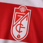 Close-up of the Granada CF crest on the 2025/26 home fan version jersey with red and white stripes.