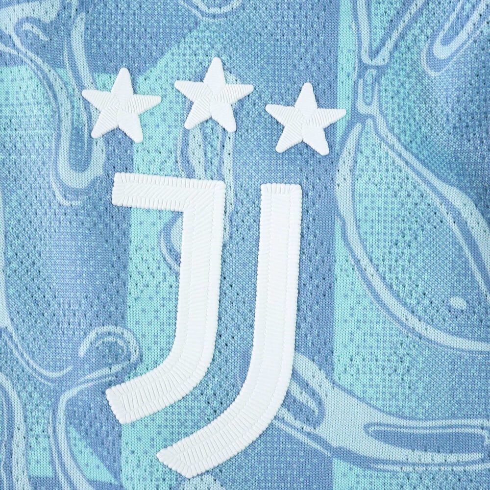 Juventus Away 2025/26 Player Version badge with three stars on a blue patterned fabric background.