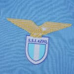 Close-up of the S.S. Lazio club crest on the 2025/26 home fan version jersey fabric.