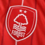 Close-up of Nottingham Forest 2025/26 home fan jersey badge with two stars and white tree emblem.