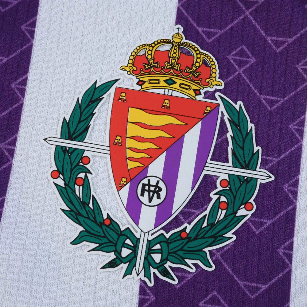 Close-up of the Real Valladolid crest on the 2025/26 home fan version jersey, purple and white background.