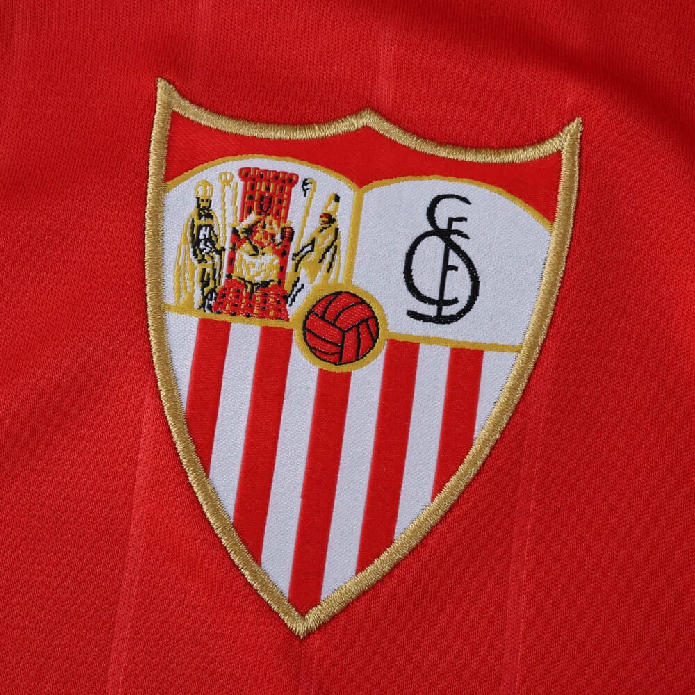Sevilla FC 2025/26 away fan jersey badge showing the club crest on red fabric.