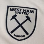 West Ham United 2025/26 away fan version badge with crossed hammers on white fabric.