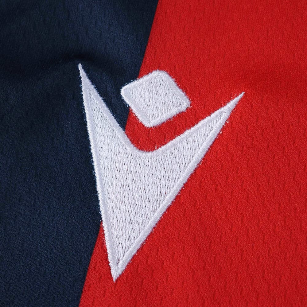 Close-up of the Bologna Home 2025/26 Fan Version jersey featuring the white Macron logo on red and navy fabric.