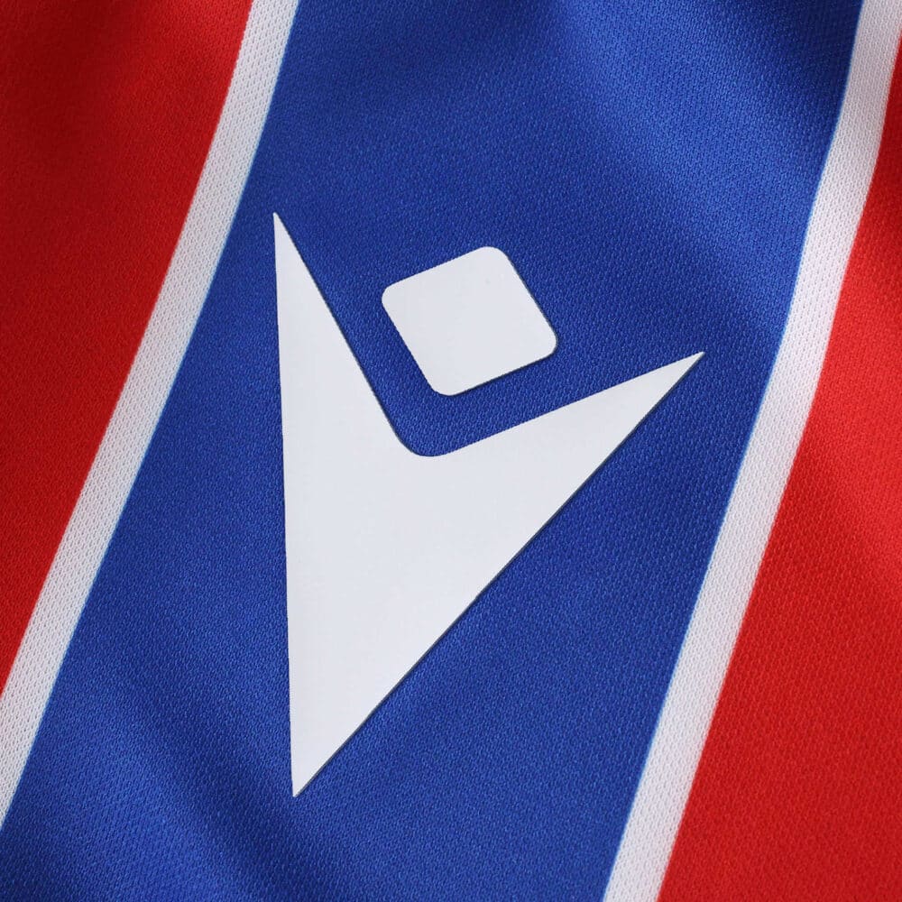 Close-up of the Crystal Palace 2025/26 home fan jersey showing the Macron logo on red and blue stripes.