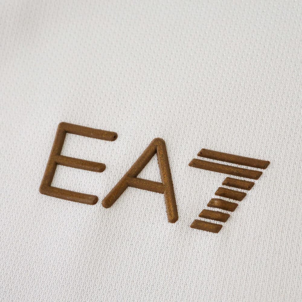Close-up of the EA7 logo on the Napoli Away 2025/26 Fan Version jersey in gold embroidery.