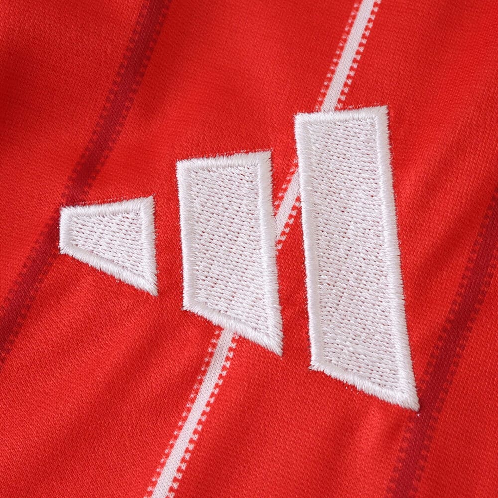 Close-up of the Nottingham Forest 2025/26 home fan jersey featuring a white Adidas logo on red fabric.