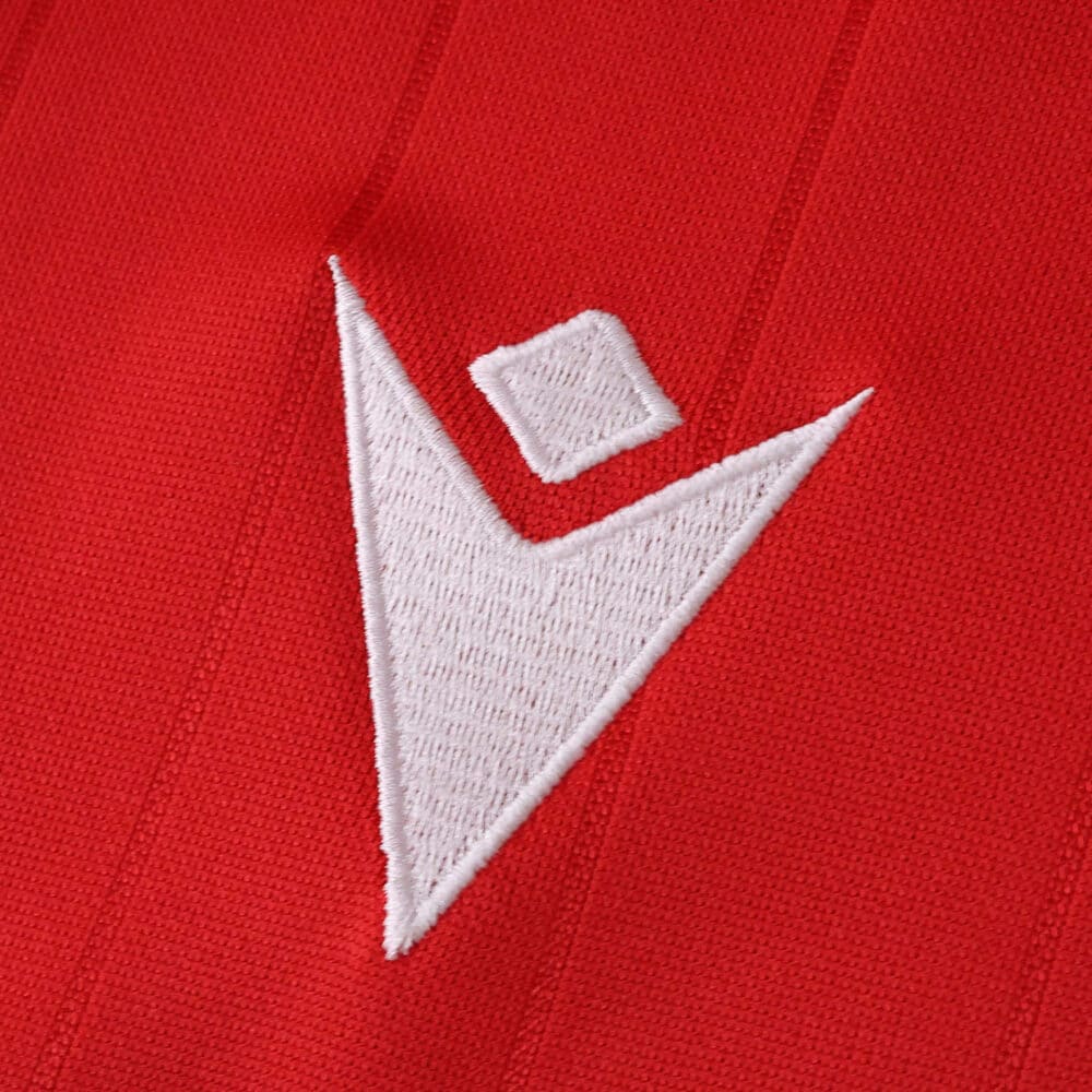Close-up of the Macron logo embroidered on the red Osasuna Home 2025/26 Fan Version jersey.