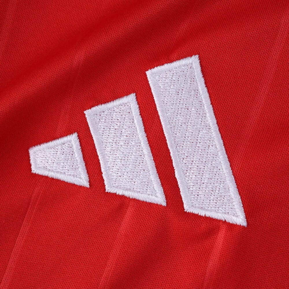 Close-up of the white Adidas logo on the red Sevilla FC Away 2025/26 Fan Version jersey.