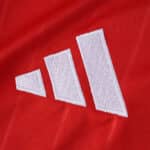 Close-up of the white Adidas logo on the red Sevilla FC Away 2025/26 Fan Version jersey.