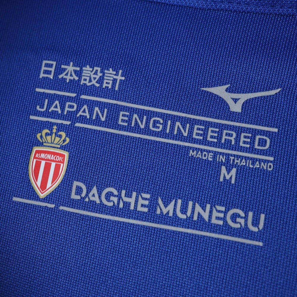 Close-up of AS Monaco Away 2025/26 Fan Version jersey tag with club crest, Mizuno logo, and sizing details.