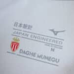 Close-up of AS Monaco Home 2025/26 Fan Version shirt label with club crest and "Japan Engineered" text.