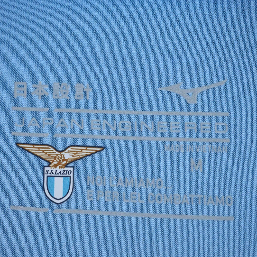 Close-up of Lazio 2025/26 home fan jersey tag with club crest and "Noi l'amiamo e per lei combattiamo" text.