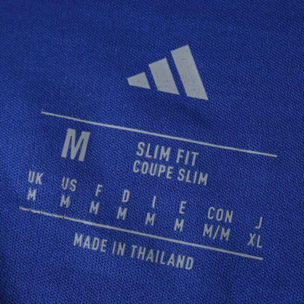 Adidas logo and size label on Leeds United Away 2025/26 Fan Version shirt, showing medium size and slim fit.