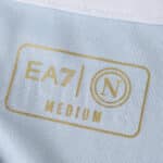 Close-up of the Napoli 2025/26 home fan jersey label showing EA7 logo, N crest, and "Medium" size.