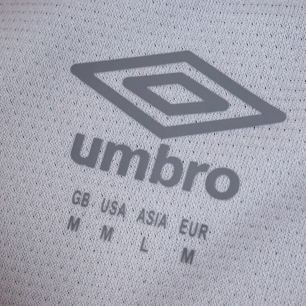 Close-up of the Umbro logo and size details on the Rayo Vallecano 2025/26 Home Fan Version jersey fabric.