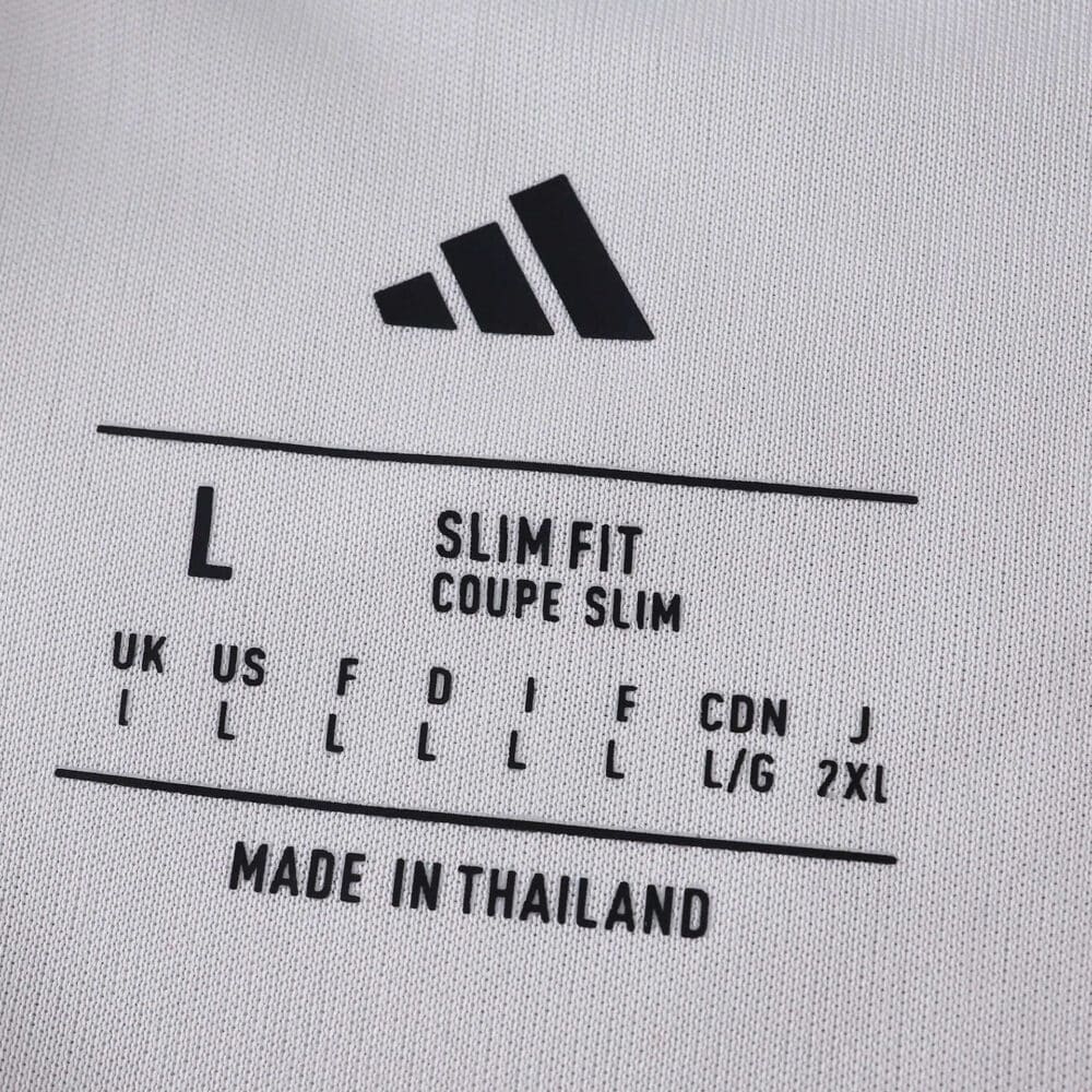 Close-up of Sevilla FC 2025/26 Home Fan Version jersey size tag with Adidas logo and sizing details.