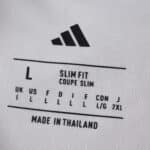 Close-up of Sevilla FC 2025/26 Home Fan Version jersey size tag with Adidas logo and sizing details.