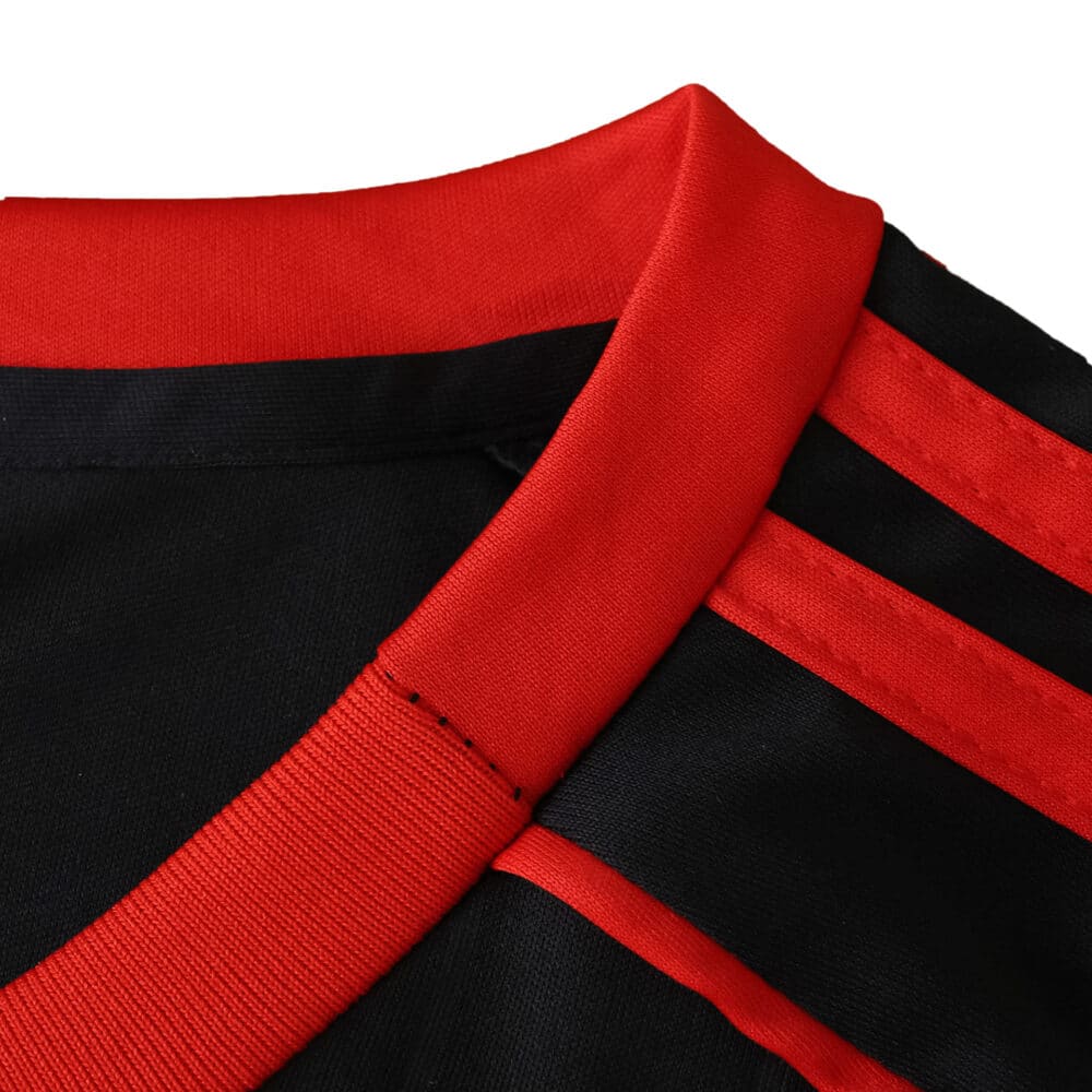 Close-up of Sevilla FC Third 2025/26 Fan Version jersey showing red collar and black fabric with red stripes.
