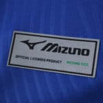 Close-up of Mizuno logo patch on the AS Monaco 2025/26 Away Fan Version jersey in blue fabric.
