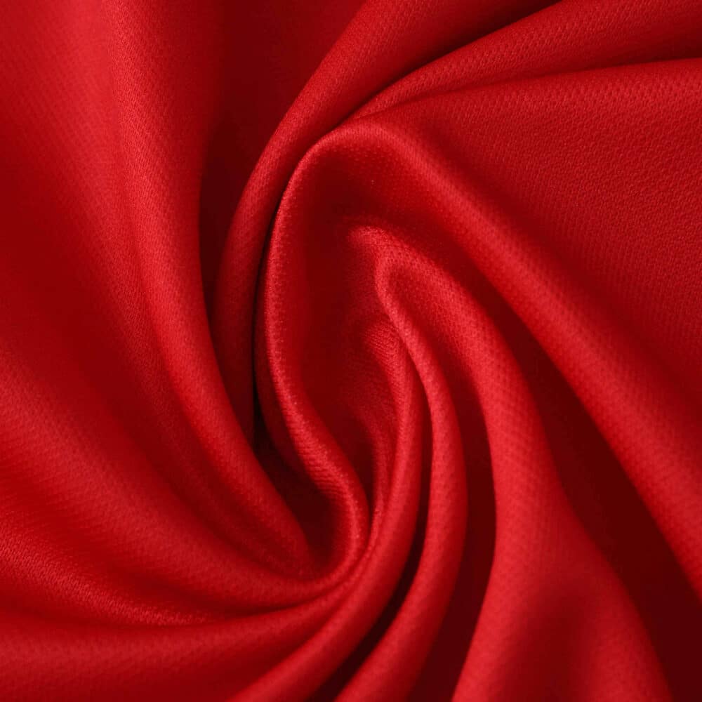 Close-up of vibrant red fabric used for the Granada Home 2025/26 Fan Version jersey.