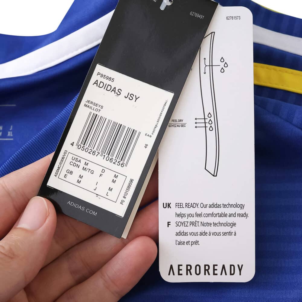 Close-up of Leeds United 2025/26 Away Fan Version jersey tags showing size, product info, and AEROREADY label.